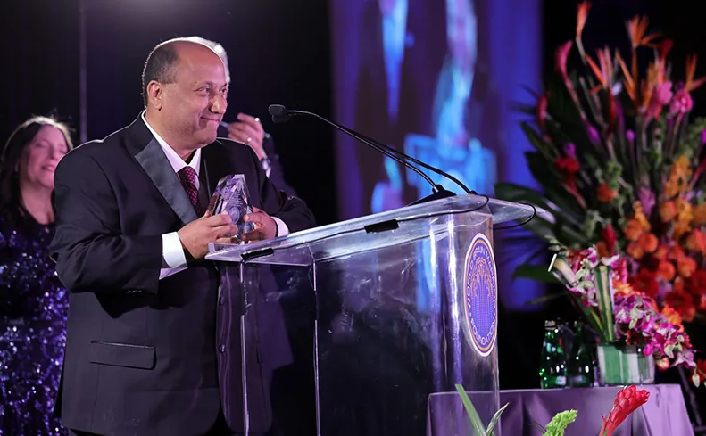 Dr. Keerthy Sunder accepting the Golden Axon Leadership Award on stage at the 2023 SBMT Gala