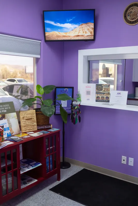 Reception area at Karma Doctors with a purple accent wall, patient reading materials and a large plant