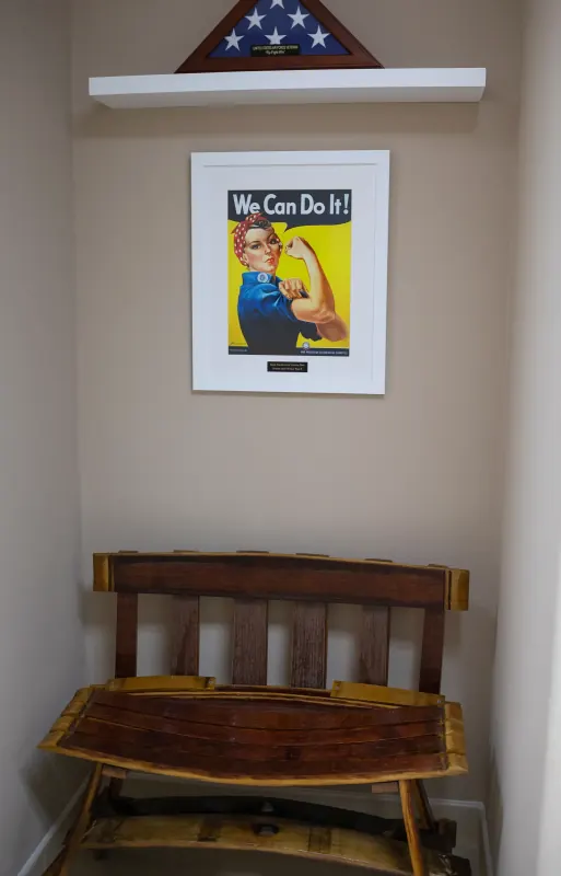 Reclaimed wood bench beneath a framed We Can Do It poster and a folded flag display