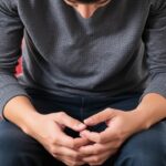 Person sitting with head down and hands clasped, showing anxiety or emotional distress